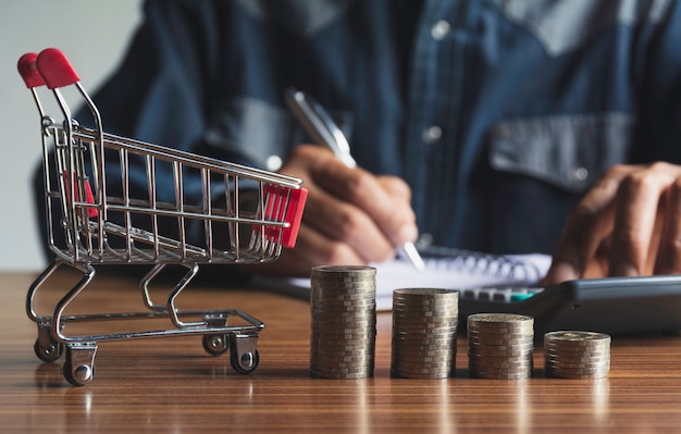 Homme d&#39;affaires avec pile de pièces d&#39;argent et panier d&#39;achat pour le concept financier et comptable.