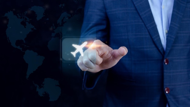 Homme d'affaires pointant le doigt touchant pour sélectionner le vol en appuyant sur le bouton d'avion à écran tactile avec fond de carte du monde Concept de transport d'avion d'affaires