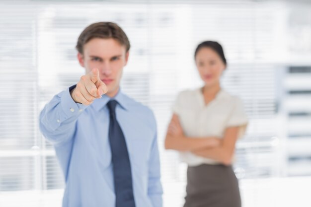 Homme d&#39;affaires pointant vers la caméra avec une femme au bureau