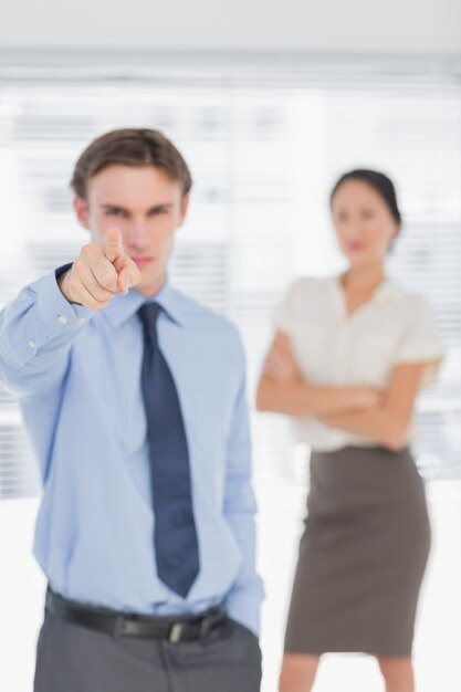 Homme d&#39;affaires pointant vers la caméra avec une femme au bureau