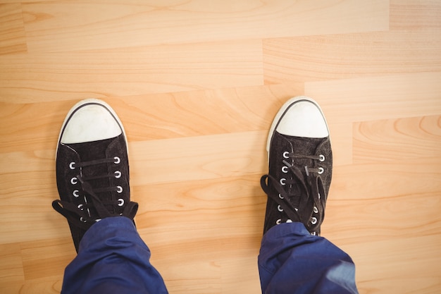 Homme d&#39;affaires portant des chaussures de toile debout sur le plancher de bois franc