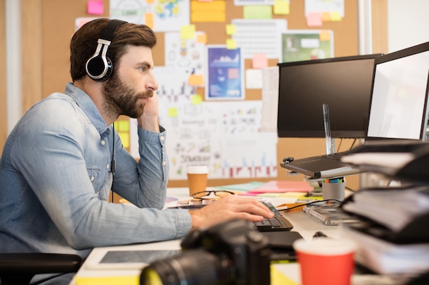 Homme d'affaires portant des écouteurs tout en travaillant au bureau de création