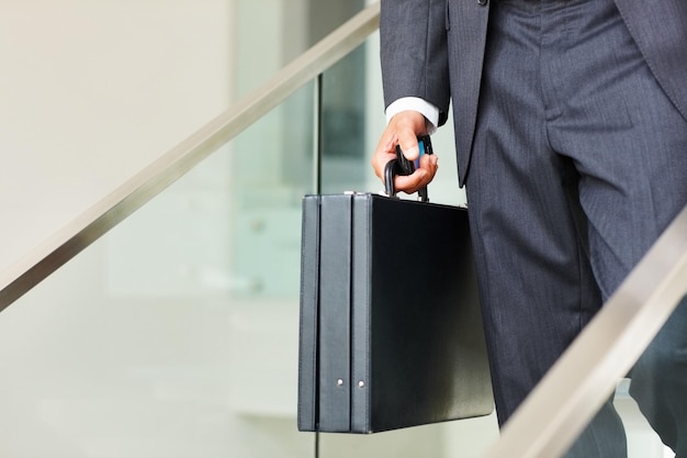 Homme d'affaires portant un téléphone portable et une valise Section basse d'un homme d'affaires portant un téléphone portable et une valise et descendant les escaliers