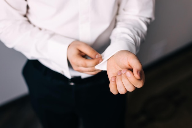 Homme d'affaires porte une chemise blanche les mains des hommes en gros plan le marié se prépare le matin avant la cérémonie de mariage