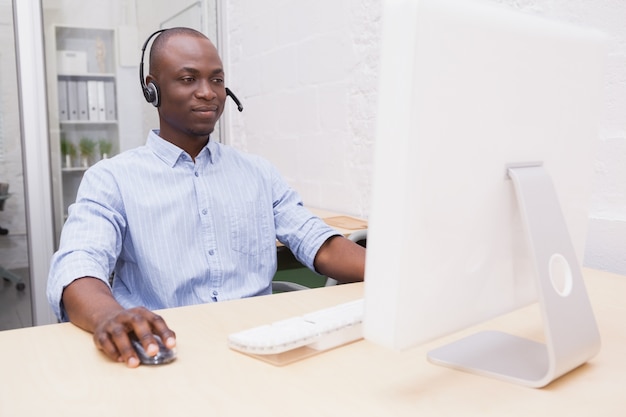 Homme d&#39;affaires, porter un casque tout en utilisant un ordinateur