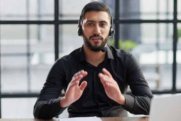 Homme d&#39;affaires positif, parler sur un casque à un ordinateur