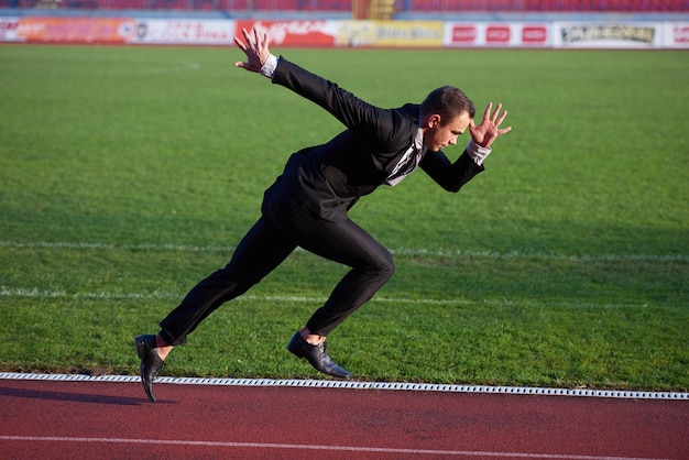 Photo homme d'affaires en position de départ prêt à courir et à sprinter sur une piste de course d'athlétisme