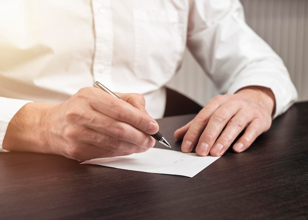 Homme d'affaires prenant une note mémo en gros plan au bureau et écrivant un rappel sur une feuille de papier