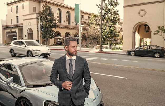 Homme d'affaires près de l'auto en plein air bel homme en costume cher confiant homme d'affaires louer une voiture