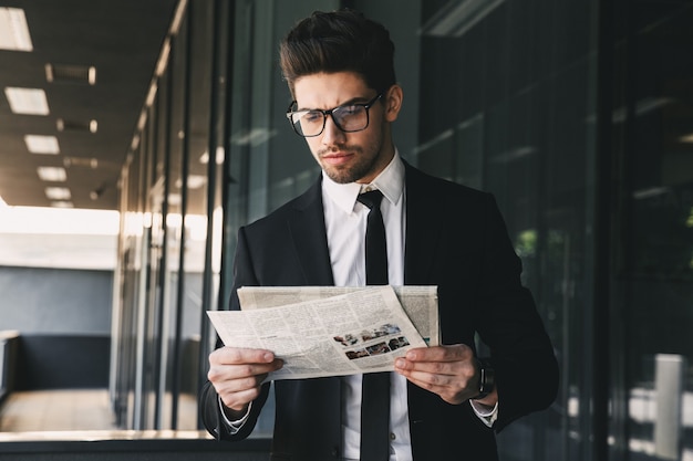 Homme d'affaires près du centre d'affaires tenant la lecture du journal.