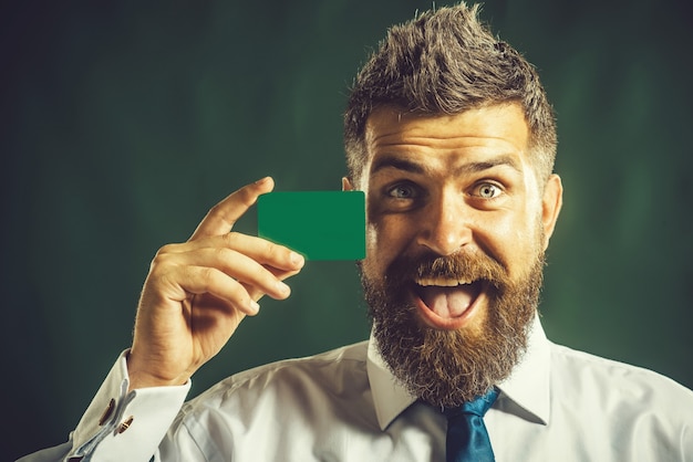 Homme d'affaires présentant la marque d'entreprise de carte de crédit homme barbu sérieux avec carte de visite vierge dans