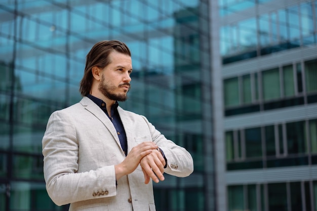 Homme d'affaires professionnel en costume regardant la caméra tout en se tenant dans la rue avec l'application de téléphone portable