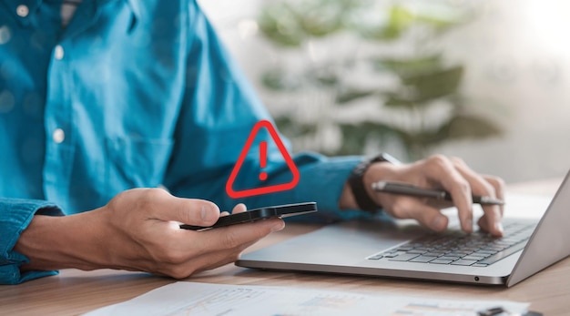 Homme d'affaires ou programmeur utilisant un ordinateur portable avec un panneau d'avertissement triangle rouge Pour les alertes d'erreur et le concept de maintenance des informations sur les virus