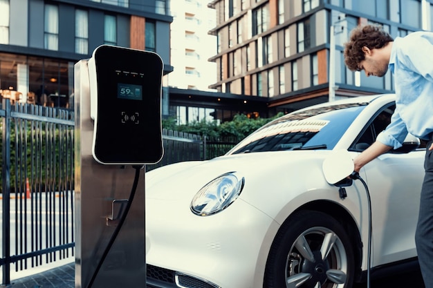 Un homme d'affaires progressiste branche la prise du chargeur de la station de charge au véhicule électrique