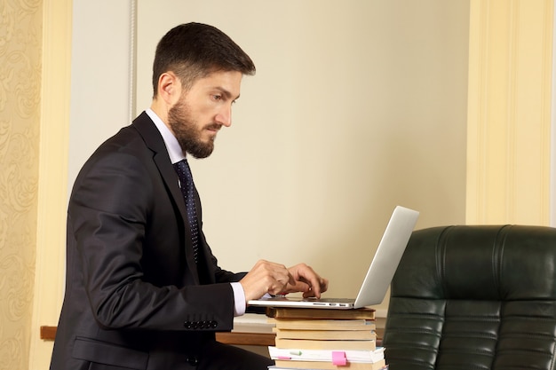 Homme d'affaires prospère au bureau travaillant avec un ordinateur portable