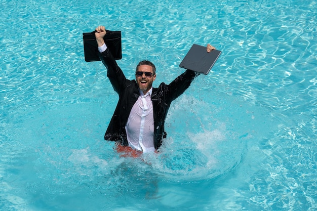 Homme d'affaires prospère en costume dans l'eau de la piscine homme d'affaires en costume travaillant sur ordinateur portable dans le caca de natation