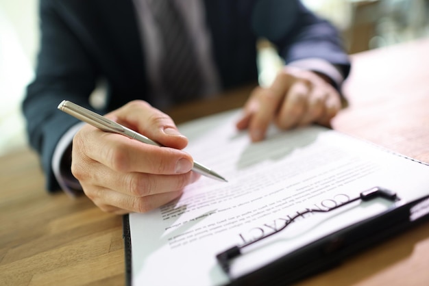 Photo un homme d'affaires prospère en costume lit les termes et conditions du contrat tenant un stylo dans la main de l'homme