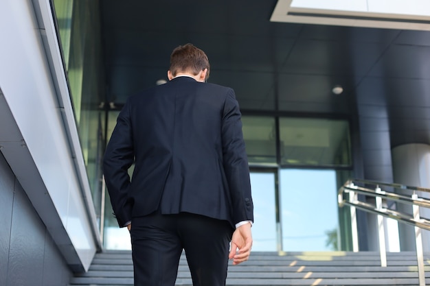 Un homme d'affaires prospère et élégant monte les escaliers de l'immeuble de bureaux.