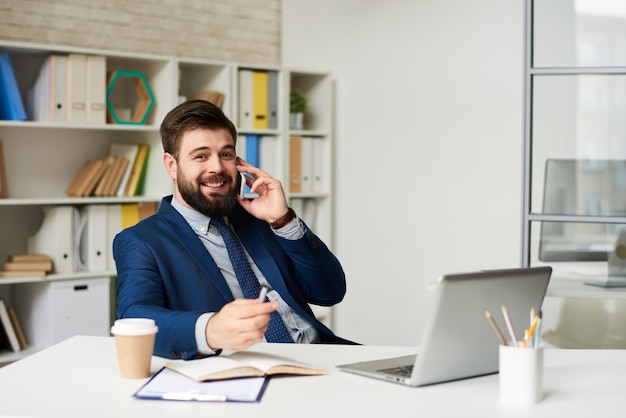 Homme d'affaires prospère, parlant par téléphone au bureau