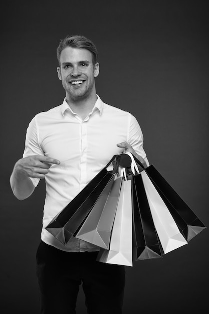 Homme d'affaires prospère shopping en ligne Les gens occupés apprécient le service en ligne Shopping en ligne Livraison d'achat Homme d'affaires utilise une application de shopping L'homme porte des sacs à provisions fond sombre