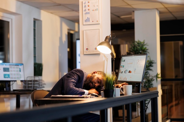 Photo un homme d'affaires qui fait une sieste sur son bureau à cause de la surcharge de travail dans un bureau de start-up un directeur exécutif accro au travail qui s'endort après avoir travaillé tard dans la nuit sur le plan d'investissement de l'entreprise concept d'entreprise