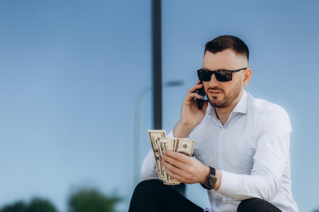 Photo un homme d'affaires qui parle au téléphone et compte des dollars.