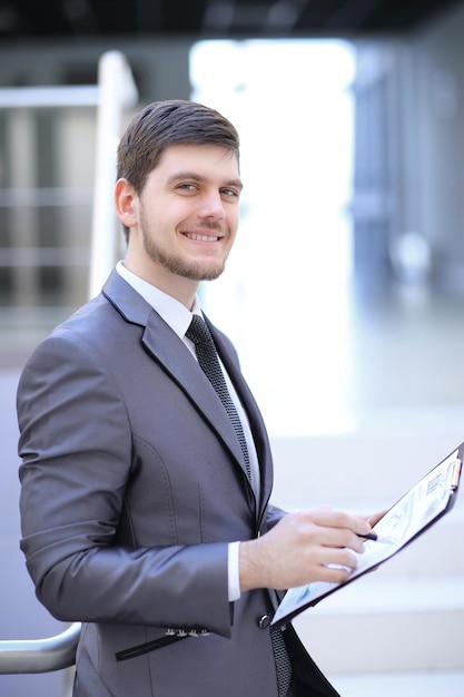 Homme d'affaires avec le rapport financier assis dans le hall du bureau