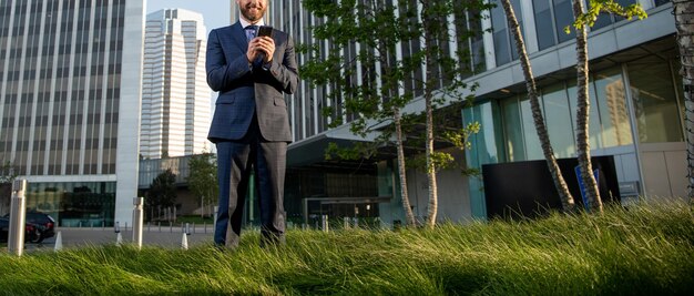 Homme d'affaires recadré en costume tapant un message sur le téléphone en dehors de la communication de bureau