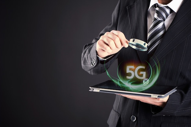 Homme d'affaires regardant la tablette avec le concept de loupe 5 G