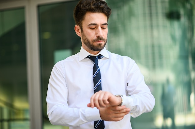 Homme d'affaires regardant le temps dans une ville moderne