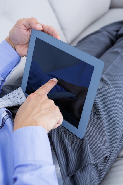 Homme d&#39;affaires relaxant sur un canapé avec une tablette