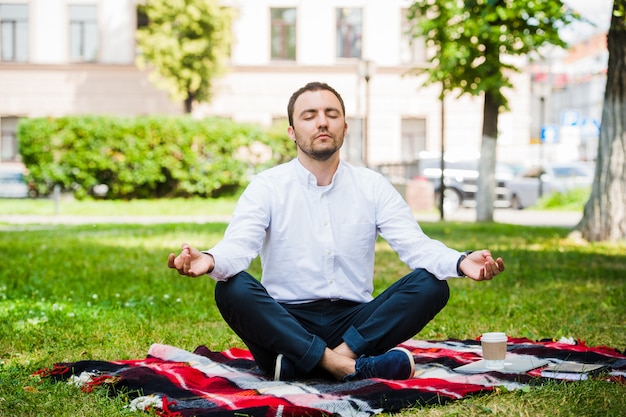 Homme d'affaires relaxant dans un parc en position du lotus