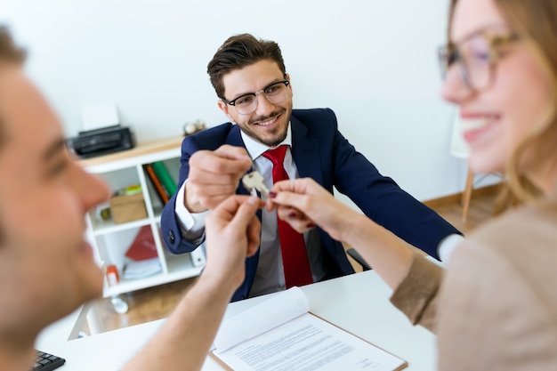 L&#39;homme d&#39;affaires remet les clés de la maison à un couple après avoir fermé la vente.