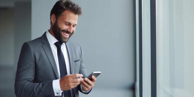 Un homme d'affaires réussi et souriant en costume se tient sur le fond d'un mur gris dans le bureau.