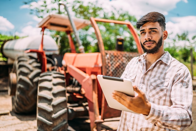 Homme d'affaires rural latin vérifiant le travail dans une tablette numérique.