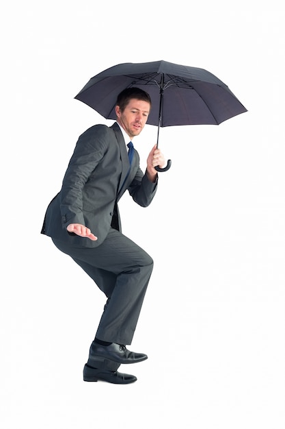 Homme d&#39;affaires s&#39;abritant sous un parapluie noir