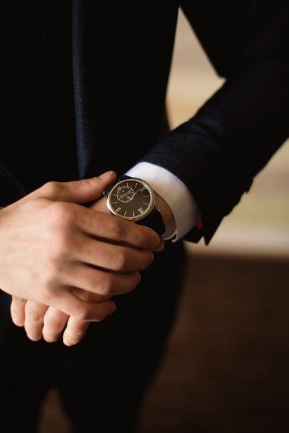 Homme d'affaires s'habille et ajuste sa montre, se préparant pour une réunion. L'horloge