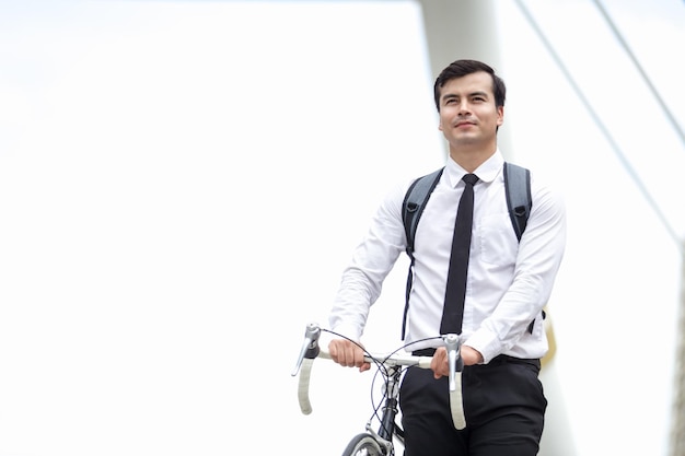 Homme d'affaires avec sac à dos à vélo dans la ville contre un ciel dégagé
