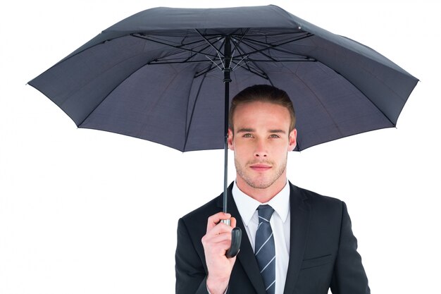 Homme d&#39;affaires sans faille s&#39;abritant sous le parapluie