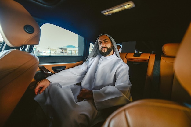 Un homme d'affaires saoudien en costume traditionnel dans une voiture