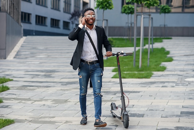 Photo homme d'affaires avec scooter électrique près d'un immeuble commercial