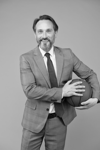 Homme d'affaires se réchauffer avec le basket-ball dans le concept de carrière sportive de bureau