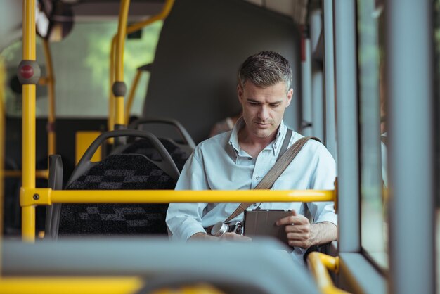 Homme d'affaires se rendant au travail en bus et travaillant avec une tablette numérique à écran tactile