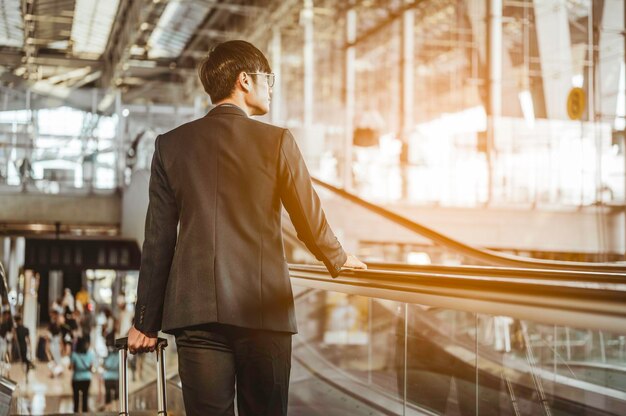 Homme d'affaires se rendant à la porte du terminal pour l'enregistrement et l'embarquement avec des bagages à l'aéroport pour un voyage d'affaires.