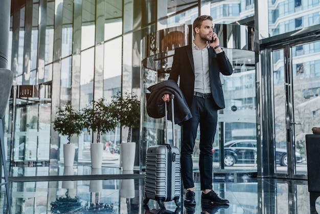 Un homme d'affaires se tient debout et parle au téléphone portable dans le couloir de l'aéroport.