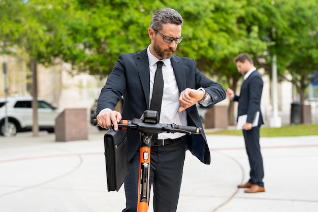 Homme d'affaires séduisant chevauchant un trottinette à new york park homme d'affaires en costume chevauchant un elec