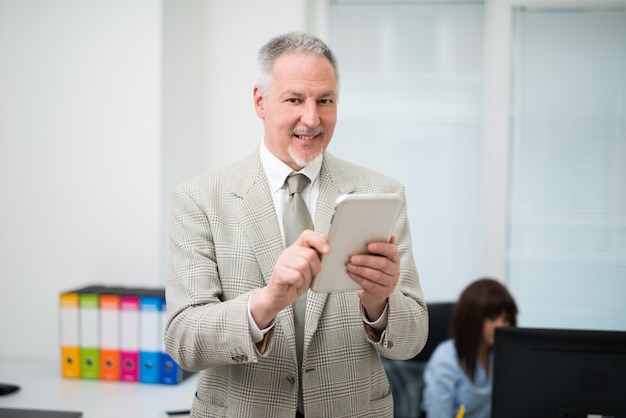 Homme d&#39;affaires senior à l&#39;aide d&#39;une tablette dans son bureau