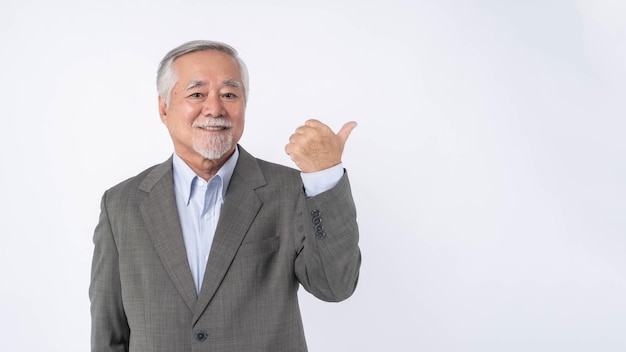 Homme d'affaires senior asiatique vieil homme avec costume se sentir heureux bonne santé pointant du doigt l'espace de copie vide pour le produit actuel ou l'espace vide pour la publicité isolé sur fond blanc