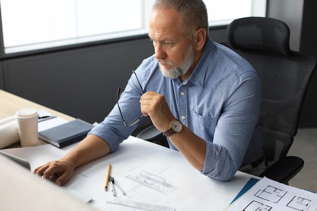 Homme d'affaires senior avec une barbe courte élégante travaillant sur un ordinateur portable à son bureau.