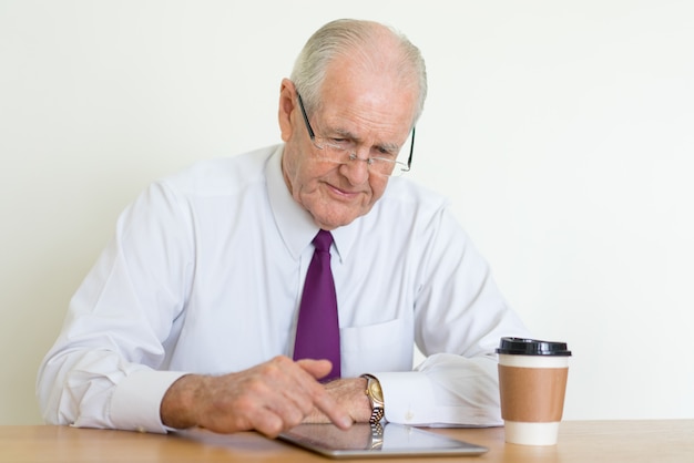 homme d&#39;affaires senior ciblé lisant des nouvelles sur la tablette tactile au bureau